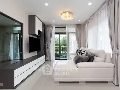 Modern living room with sleek design and large windows offering natural light and garden view.