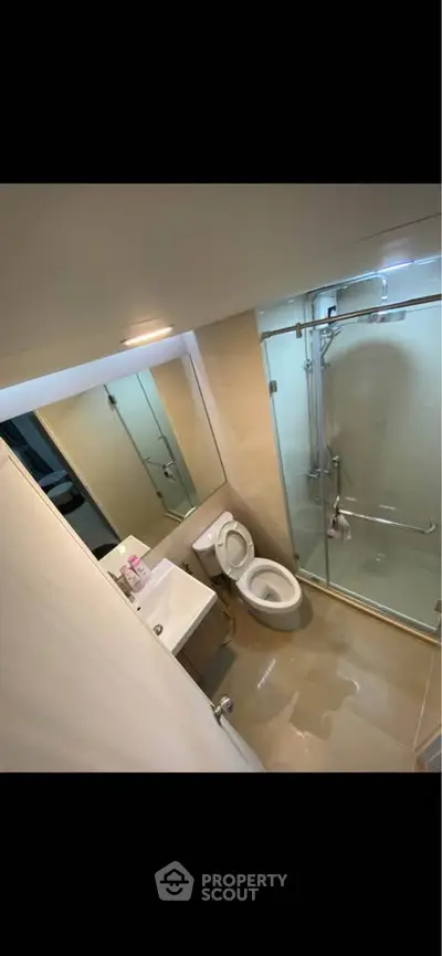 Modern bathroom with glass shower and sleek fixtures in contemporary apartment.