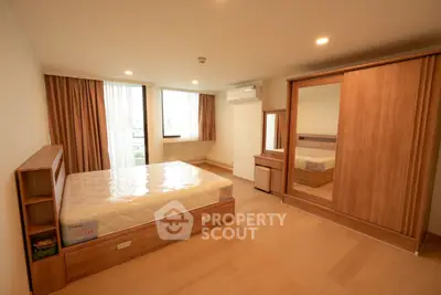 Spacious bedroom with wooden furniture and large windows in modern apartment