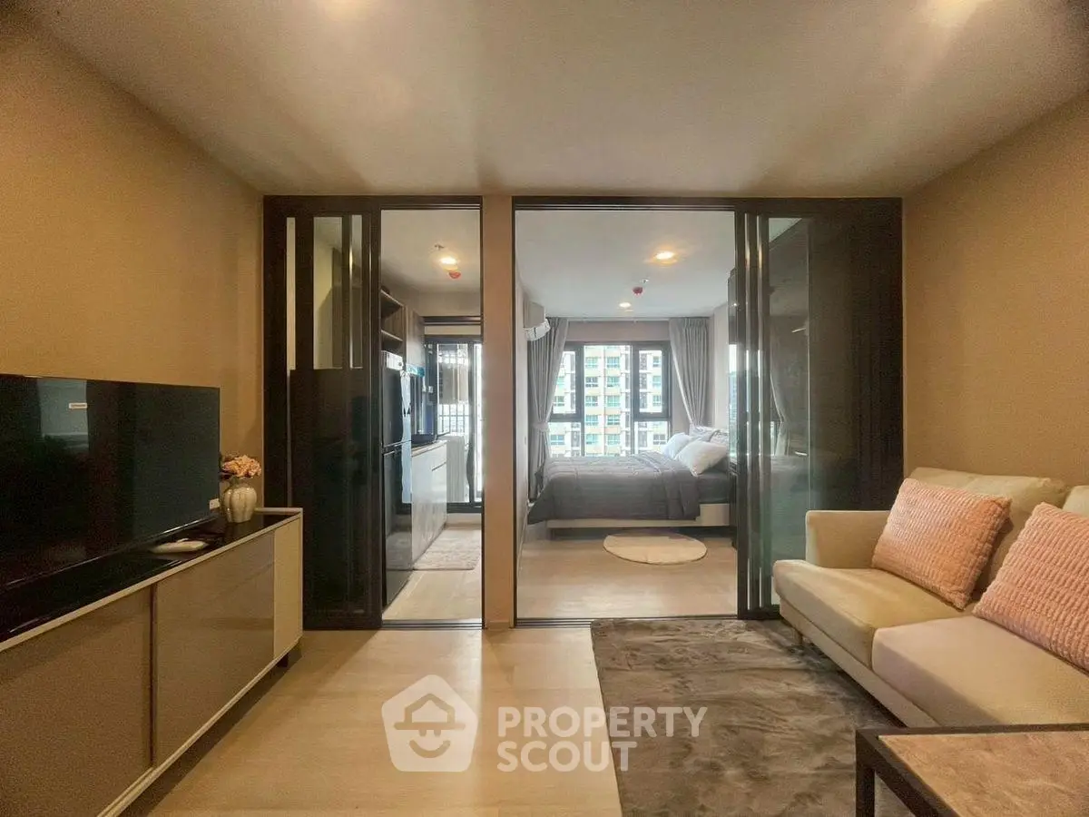 Modern living room with sliding glass doors leading to a cozy bedroom, featuring stylish decor.
