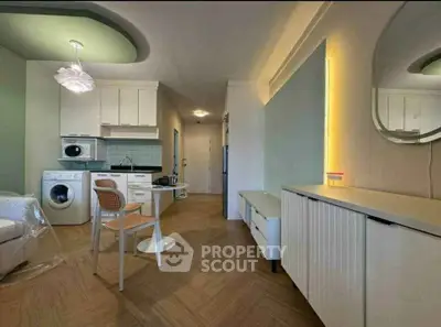 Modern open-plan living room with integrated kitchen, featuring washing machine and stylish decor.