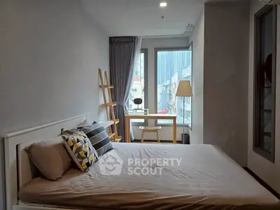 Modern bedroom with stylish decor and city view, featuring a cozy bed and a work desk by the window.
