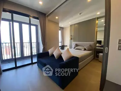 Modern bedroom with large windows and balcony access, featuring stylish decor and ample natural light.