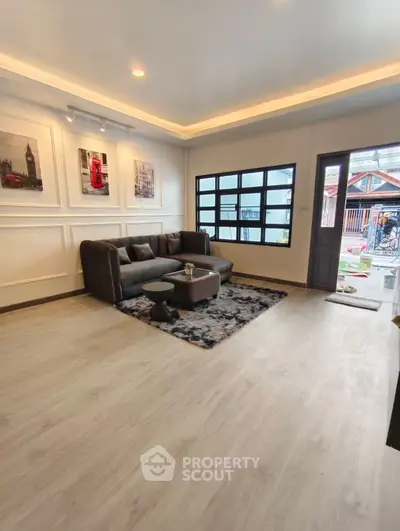 Modern living room with stylish decor and large window, featuring cozy seating and elegant flooring.