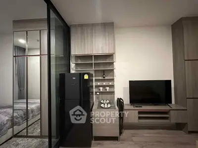 Modern studio apartment with sleek design, featuring a compact kitchen and cozy living area with a TV.