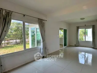 Spacious living room with large windows and garden view, perfect for natural light lovers.