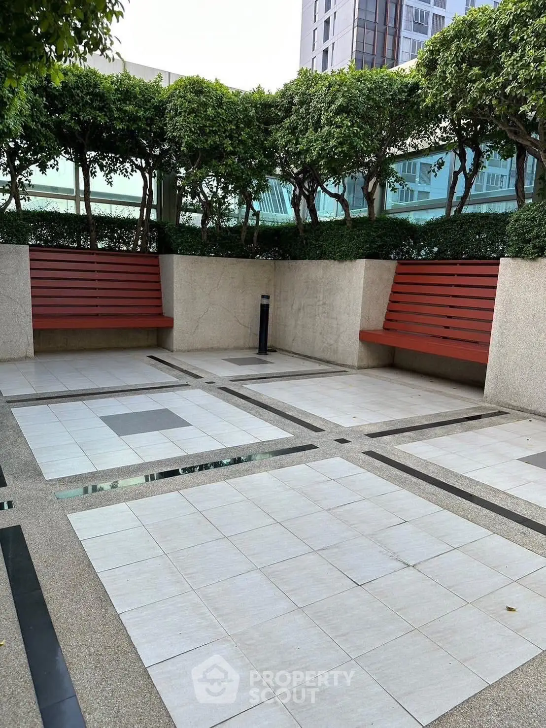 Modern outdoor seating area with benches and greenery in a residential complex