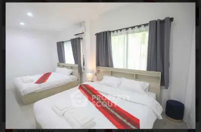 Spacious bedroom with two beds and modern decor, perfect for comfortable living.