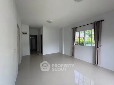 Spacious unfurnished room with large window and neutral tones, perfect for customization.