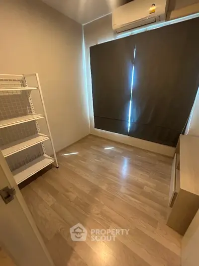Cozy small room with wooden flooring and air conditioning, ideal for storage or study.