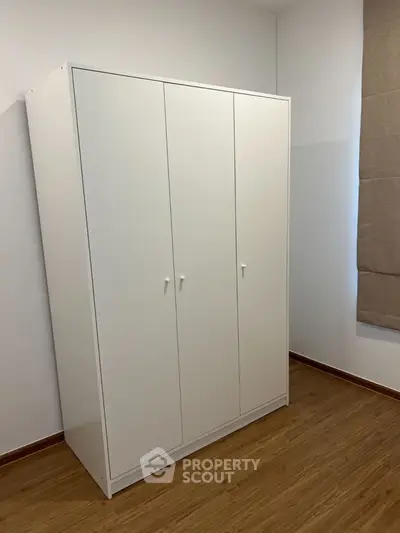 Spacious white wardrobe in a modern bedroom with wooden flooring.