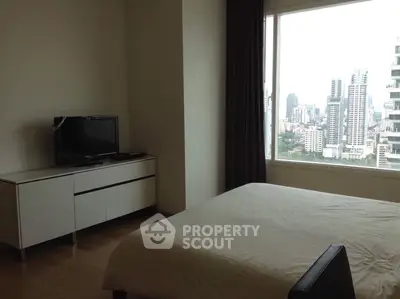 Modern bedroom with city view and sleek furniture in high-rise apartment.