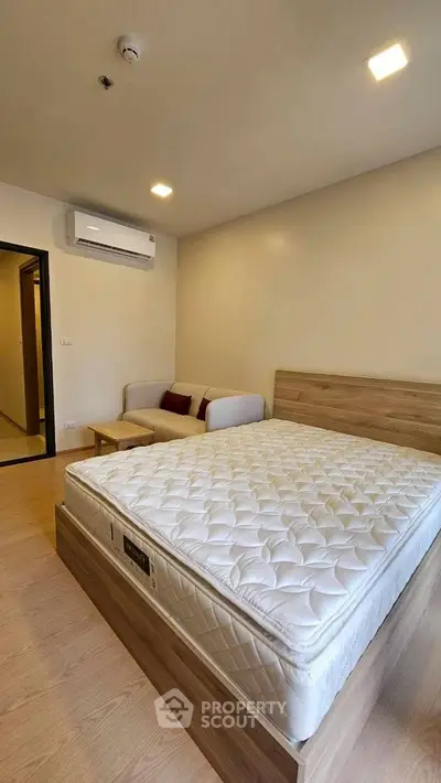 Modern bedroom with cozy bed and stylish sofa in a well-lit apartment
