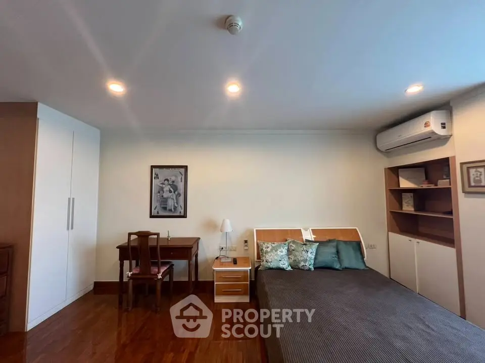 Spacious bedroom with modern decor and air conditioning, featuring wooden flooring and ample storage space.