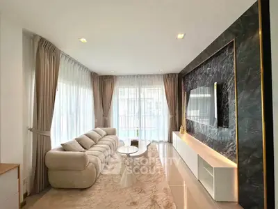 Luxurious living room with plush sofa, elegant marble wall, and large windows for natural light.