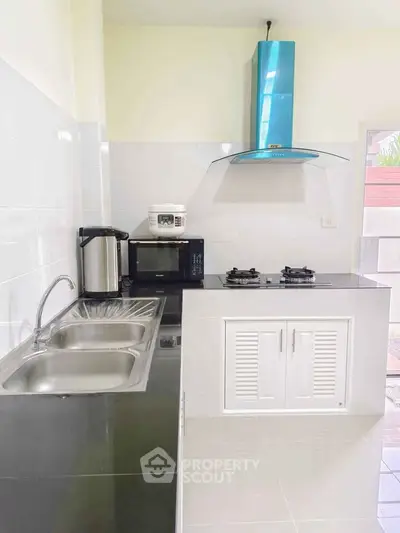 Modern kitchen with sleek design, featuring gas stove, microwave, and stainless steel sink.