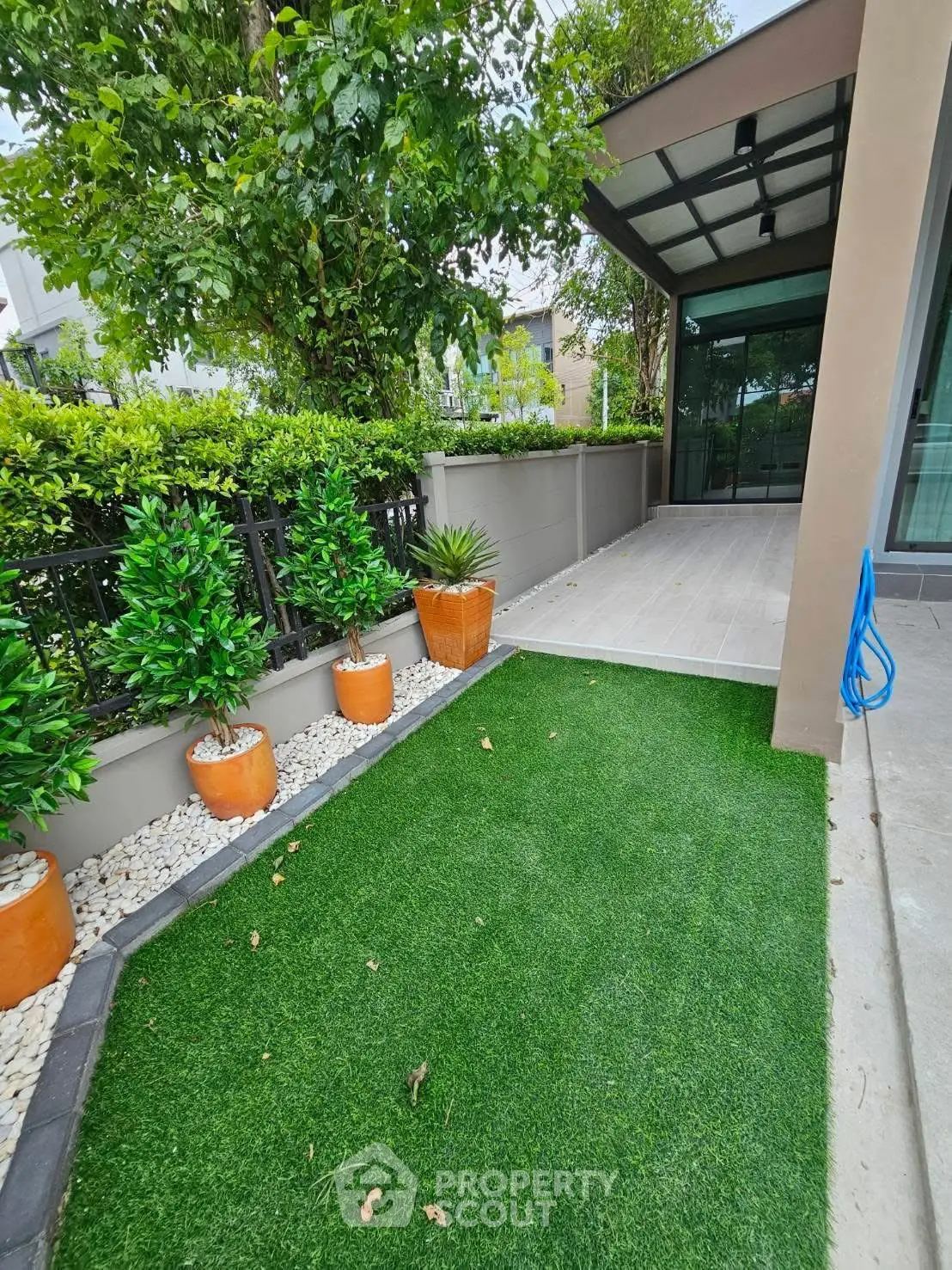 Charming garden area with artificial grass and potted plants in modern home exterior