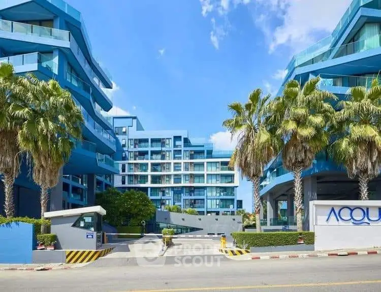 Modern blue apartment complex with palm trees and clear sky
