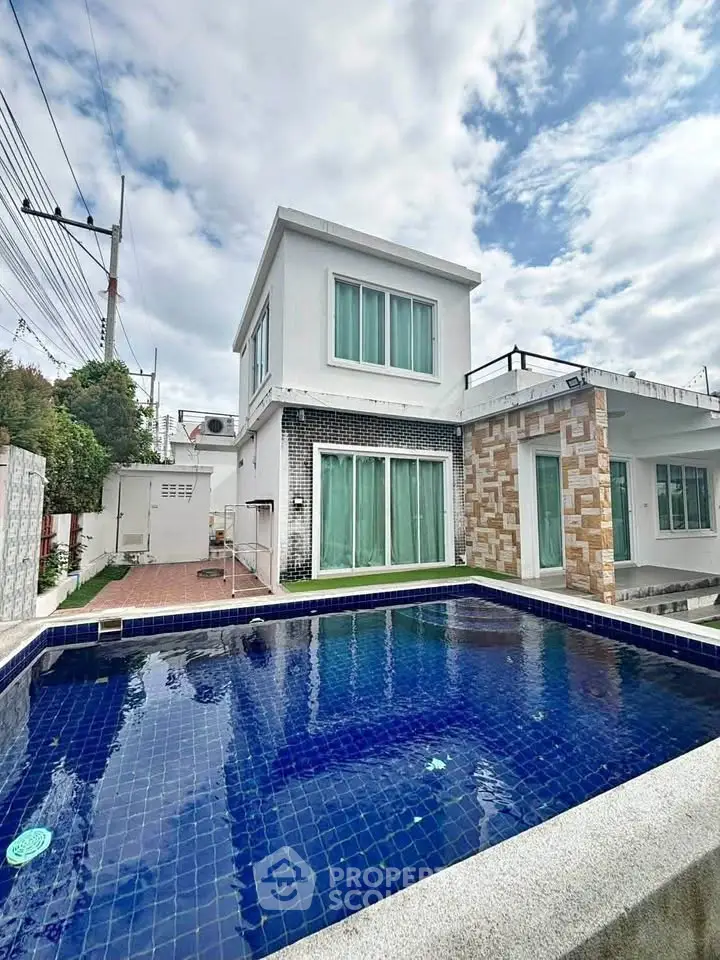 Modern two-story house with private pool and stylish exterior design under a clear blue sky.