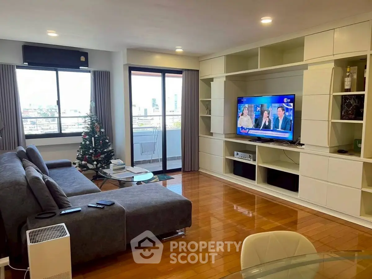 Spacious living room with modern decor and city view balcony, perfect for relaxation and entertainment.