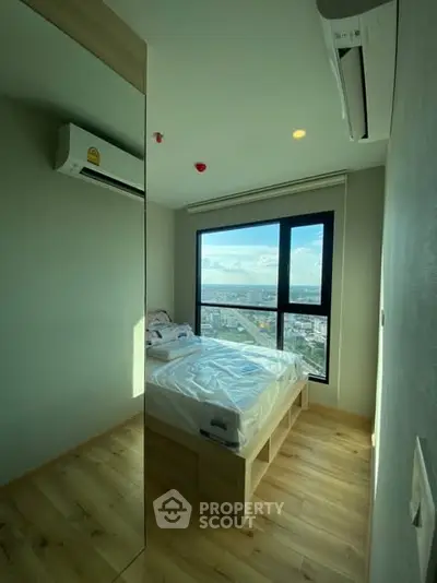 Cozy bedroom with large window offering stunning city view and modern air conditioning.