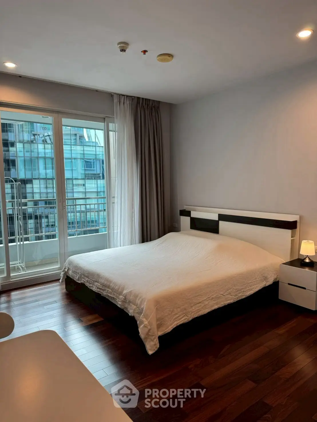 Spacious bedroom with modern decor and balcony view in urban apartment