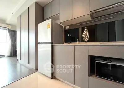 Modern kitchen with sleek cabinetry, stainless steel fridge, and built-in microwave in a stylish apartment.
