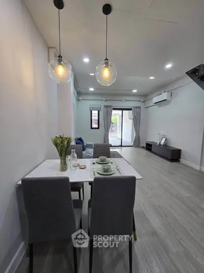 Modern living room with dining area, stylish lighting, and elegant decor in a contemporary apartment.