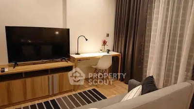 Modern living room with sleek TV setup and cozy workspace by the window.