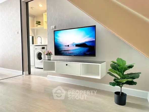 Modern living space with wall-mounted TV and washing machine in sleek interior.