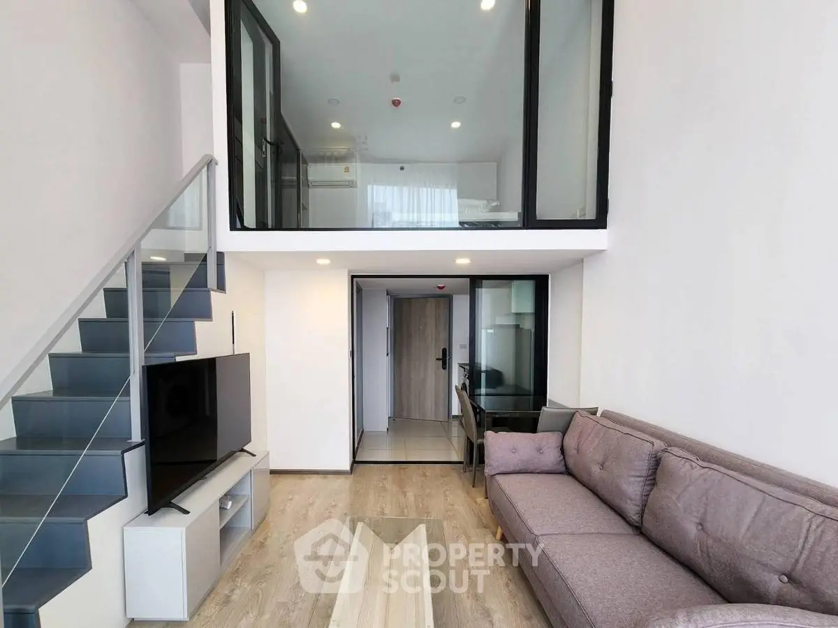 Modern duplex living room with stylish glass staircase and cozy seating area