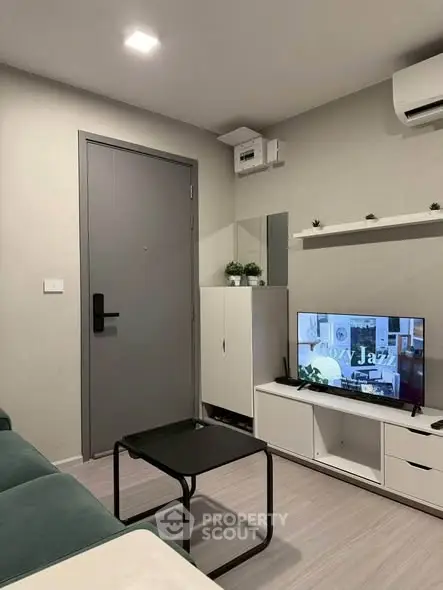 Modern living room with sleek furniture and wall-mounted TV in a cozy apartment.