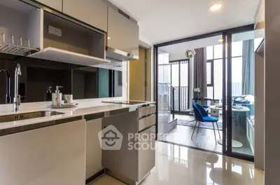 Modern open kitchen with sleek design leading to a stylish living area and balcony view.