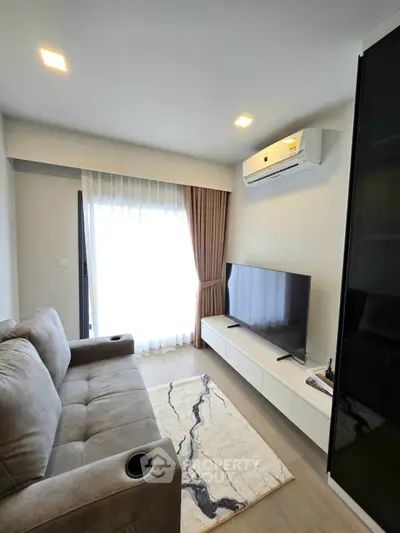 Modern living room with cozy sofa, TV, and air conditioning, featuring elegant decor and natural light.
