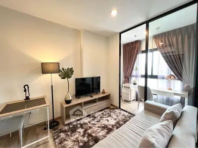 Modern living room with cozy sofa, TV, and stylish decor leading to a bright study area.