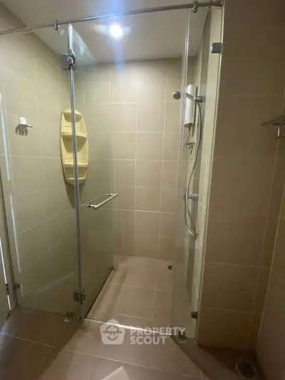 Modern bathroom with glass shower enclosure and beige tiles