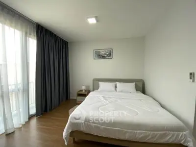 Spacious bedroom with modern decor and large window for natural light