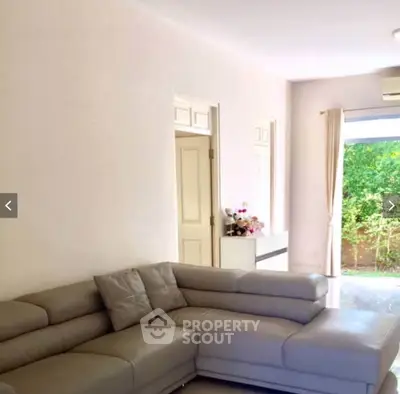 Spacious living room with modern sofa and garden view, perfect for relaxation and entertaining.