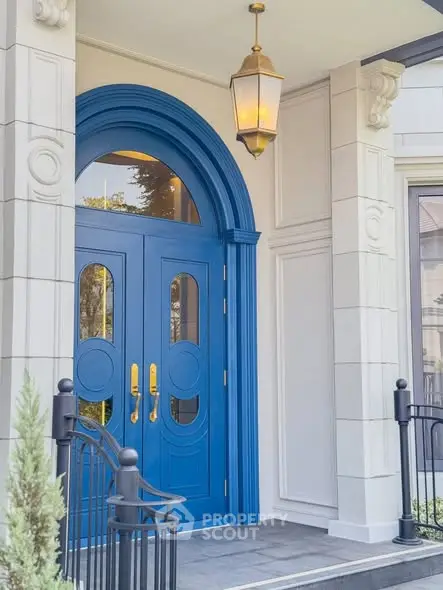 Elegant blue entrance door with classic architectural details and lantern lighting.