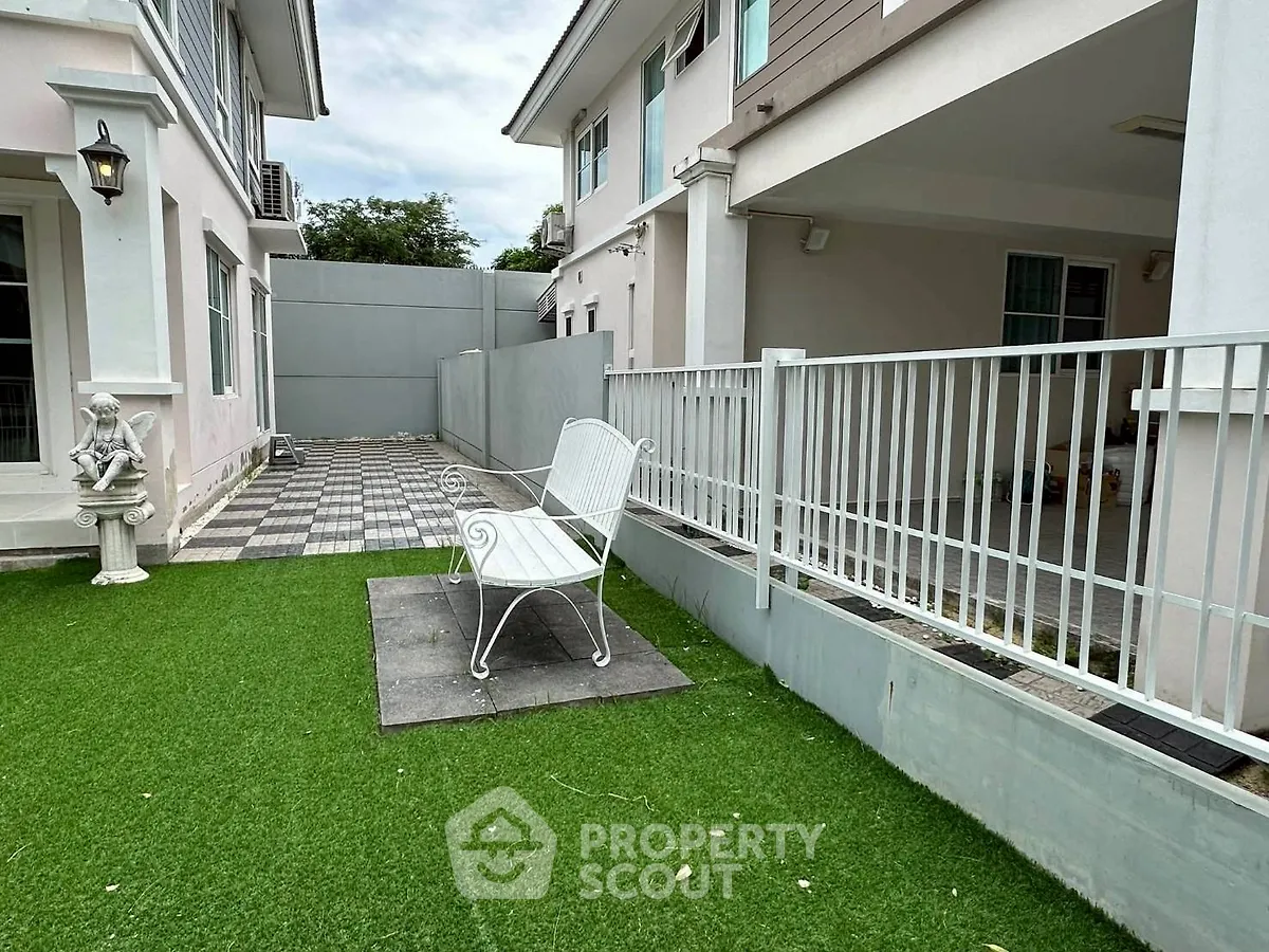Charming residential backyard with artificial grass and elegant white bench, perfect for relaxation.