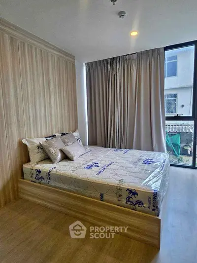 Modern bedroom with large window and stylish wooden flooring in a cozy apartment.