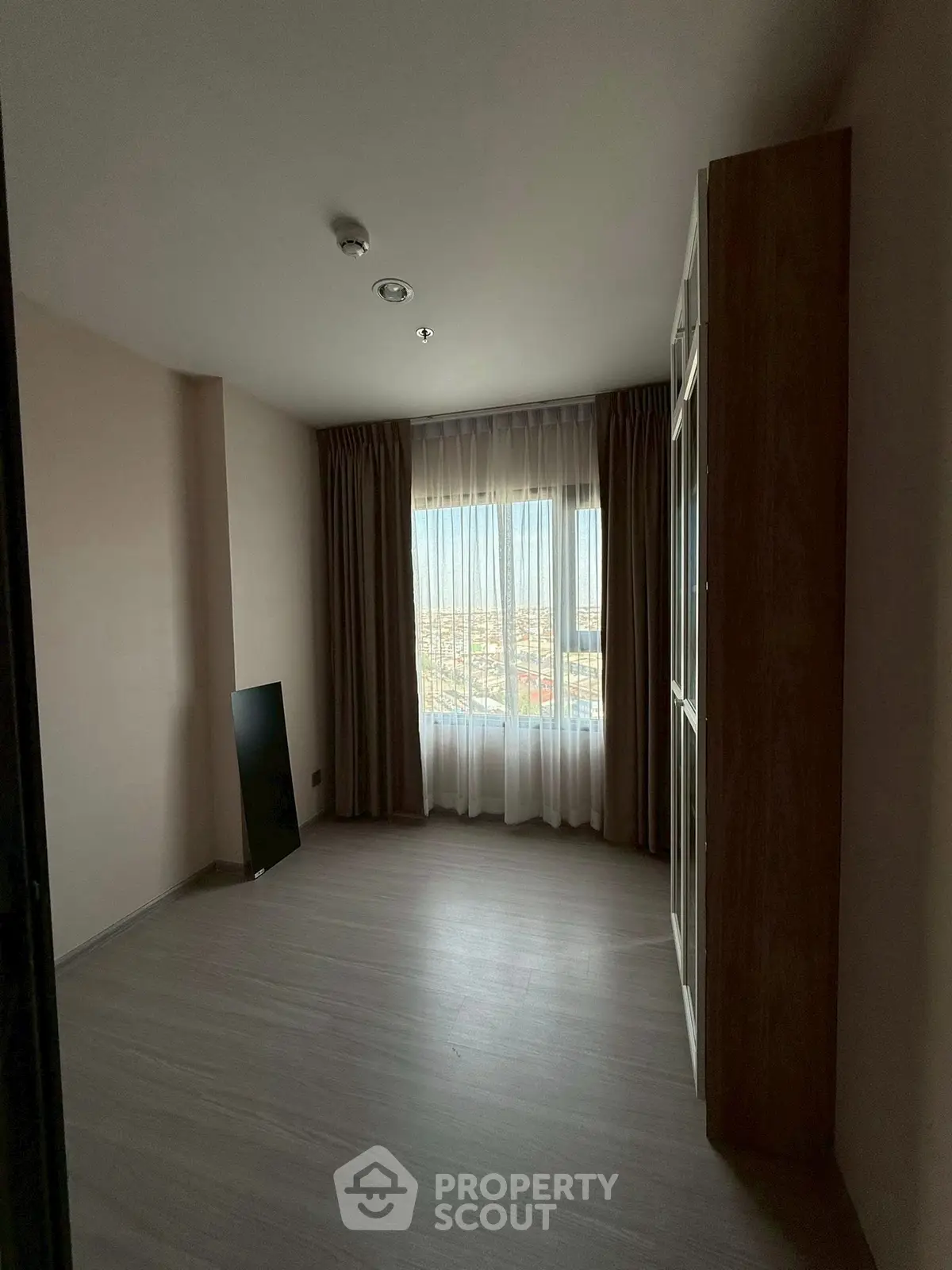 Spacious empty room with large window offering stunning city view