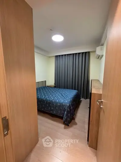 Cozy bedroom with wooden flooring and modern furnishings in a stylish apartment.