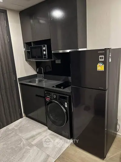 Modern compact kitchen with sleek black cabinets, built-in appliances, and stylish flooring.