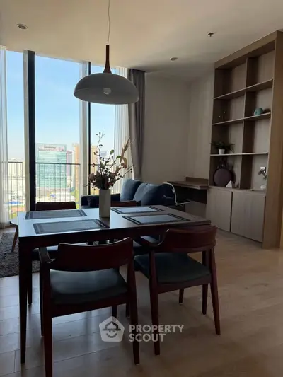 Modern living room with elegant dining area and large windows offering city views.