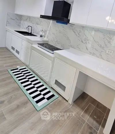Modern kitchen with sleek white cabinetry and marble backsplash