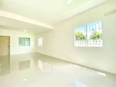 Spacious and bright empty living room with large windows and glossy tiled floor.