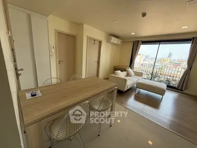 Modern living room with city view, featuring sleek furniture and large windows for natural light.