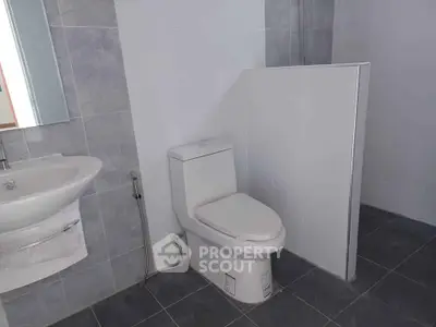 Modern bathroom with sleek white fixtures and gray tile flooring.