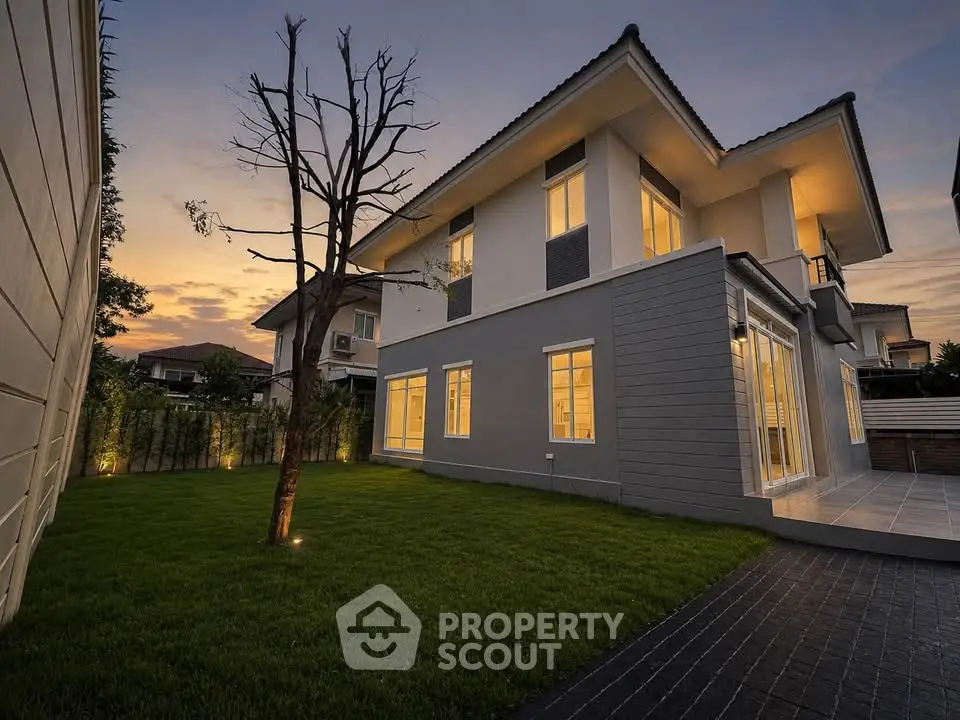 Stunning modern home exterior with lush garden and evening ambiance lighting.